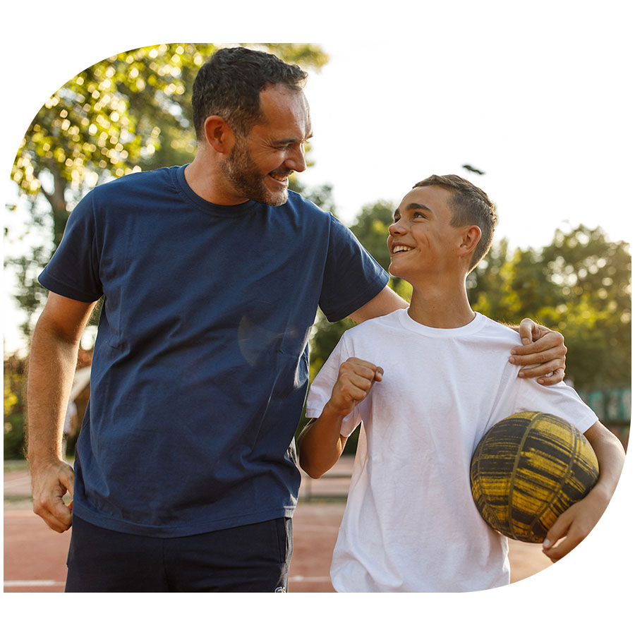 A father and son in the park smiling after playing basketball