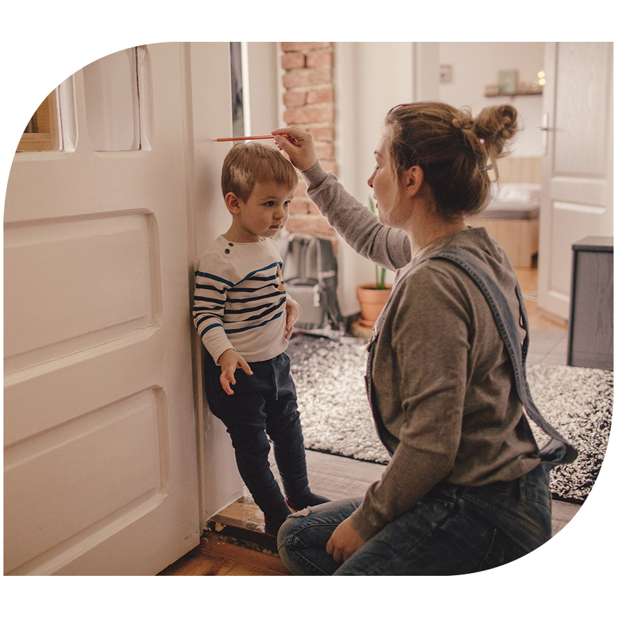 A mother marking her son's height on a doorframe of their home